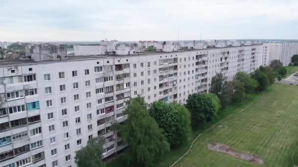 Vista aérea de largas casas de paneles de varios pisos y bloques de ciudades entre los árboles sobre el fondo del cielo de verano — Vídeo de stock