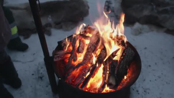 Een groep toeristen staat rond een ijzeren haard met een kampvuur. Winterreizen — Stockvideo