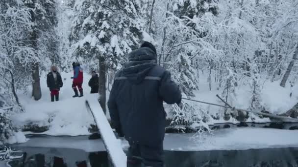 Regio Moermansk, Rusland - 10 januari 2021: Extreme winterwandeling. Toeristen steken de rivier over op een houten plank die een touw vasthoudt — Stockvideo