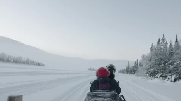 Regione di Murmansk, Russia - 10 gennaio 2021: i turisti cavalcano una motoslitta attraverso un campo di neve. Vista posteriore. Colpo palmare punto di vista della fotocamera — Video Stock