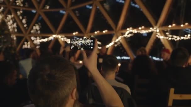 Вечеринка в большом иглу со стеклянным куполом и крупным планом по телефону — стоковое видео
