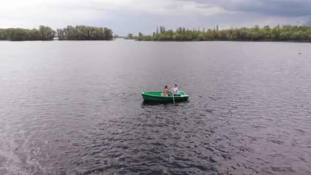 Sparatoria drone di una ragazza e un uomo su una barca a remi sul fiume durante una passeggiata di campagna in un giorno d'estate — Video Stock