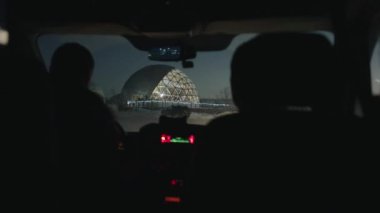 Gece aydınlatmayla parlayan cam kubbeli evlerdeki araba kulübesinin görüntüsü.