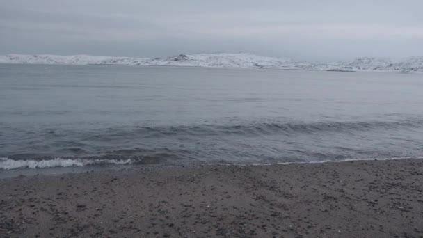 Pittoreska kustlandskap och en vik omgiven av snöiga åsar med vågor som rinner på sanden — Stockvideo