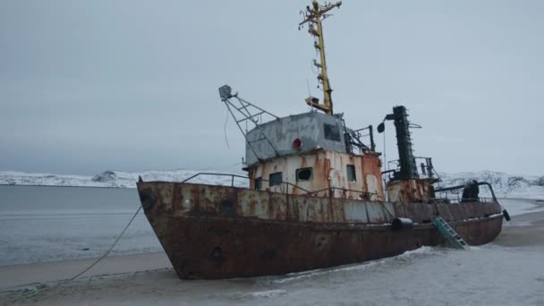 Вид на старый брошенный корабль на берегу моря и людей на палубе во время зимней поездки в село Териберка — стоковое видео