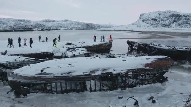 Tourists walk through the cemetery of old abandoned ships on the sea coast near the settlement of Teriberka — Stock Video