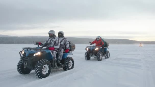 Région de Mourmansk, Russie - 10 janvier 2021 : Un groupe de touristes en combinaisons spéciales et casques roulent sur un quadro-vélo sur un champ de neige — Video