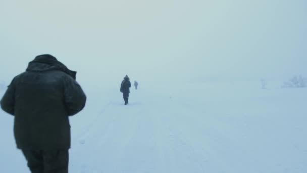 Un groupe de touristes traverse un champ neigeux par une journée d'hiver brumeuse — Video