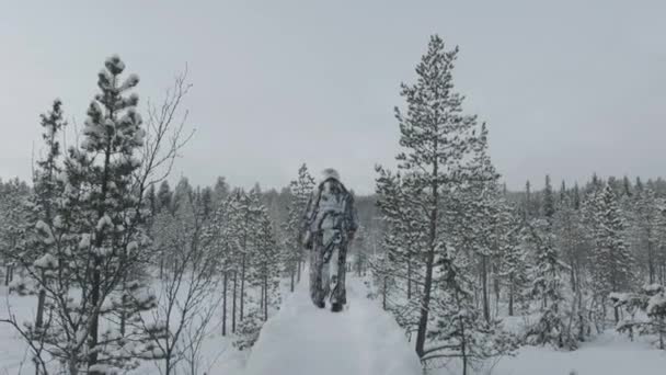 Regione di Murmansk, Russia - 10 gennaio 2021: Un gruppo di turisti in casco percorre il sentiero che conduce alla vecchia chiesa di legno nella foresta invernale — Video Stock