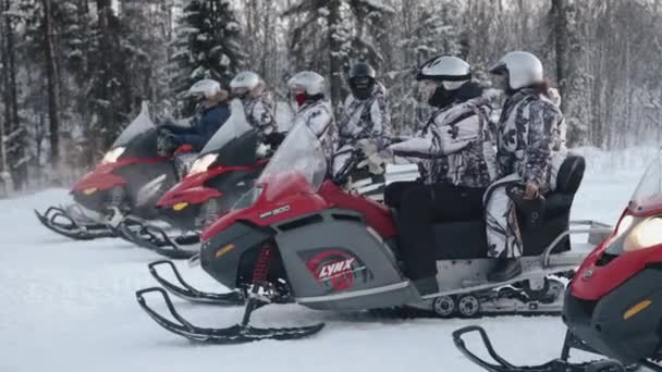 Murmansk περιοχή, Ρωσία - 10 Ιανουαρίου 2021: Snowmobiles με τουρίστες με ειδικά κοστούμια και κράνη σταθεί στη σειρά στην αρχή στο δρόμο στο δάσος το χειμώνα — Αρχείο Βίντεο