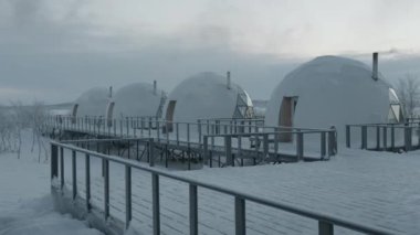 Cam panoramik pencereli igloo kubbeli evler bir kış günü glamping 'de ahşap bir platformda dikiliyorlar.