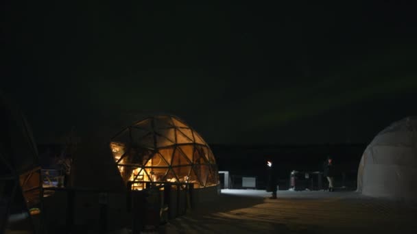 Murmansk region, Rússia - 10 de janeiro de 2021: Timelapse. Turistas com telefones e câmeras caminham na plataforma entre os iglus e tiram fotos das luzes do norte — Vídeo de Stock