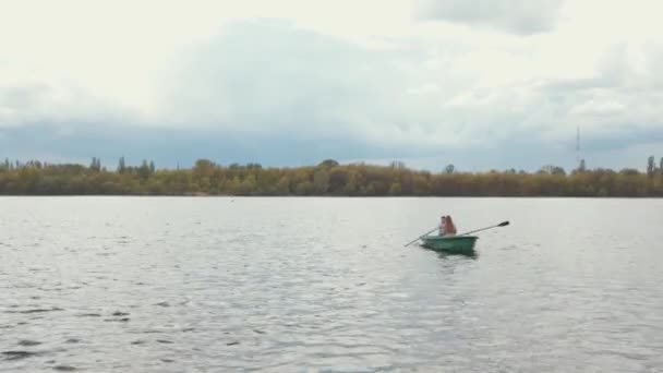 En man och en ung kvinna åker båt på en lugn sjö omgiven av träd. Kärlek och lycka koncept — Stockvideo