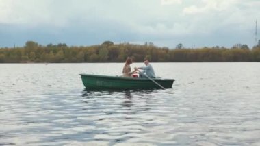 Birbirine aşık genç bir çift bir yaz günü nehirde kayıkla geziyor. Mutluluk ve huzur kavramı. Yavaş çekim
