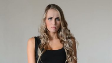 Hayal kırıklığı. Genç kadın gri arka plan üzerinde vurguladı.