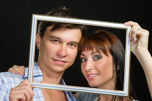 Young couple having fun making faces through frame — Stock Photo, Image