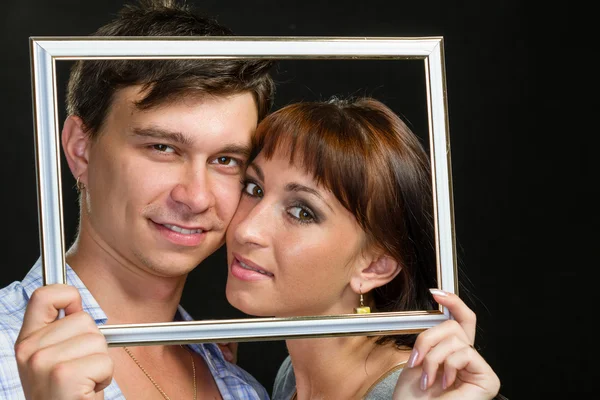 Junges Paar hat Spaß dabei, Gesichter durch Rahmen zu machen — Stockfoto