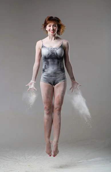 Beautiful expressive ballet dancer jumping with flour at studio — Stock Photo, Image