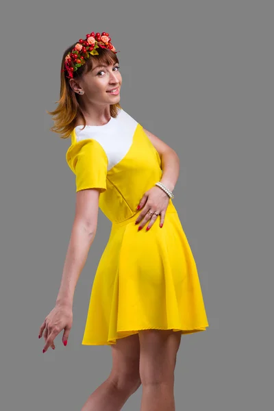 Woman in yellow dress with red wreath isolated on gray — Stock Photo, Image