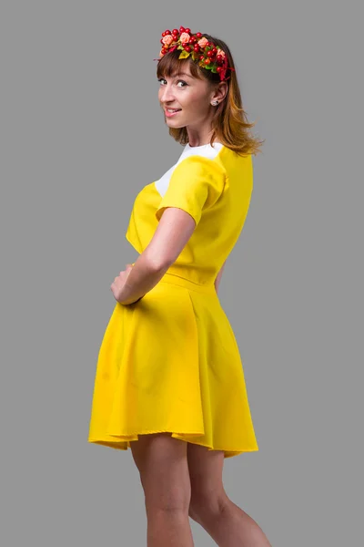 Femme en robe jaune avec couronne rouge isolée sur gris — Photo