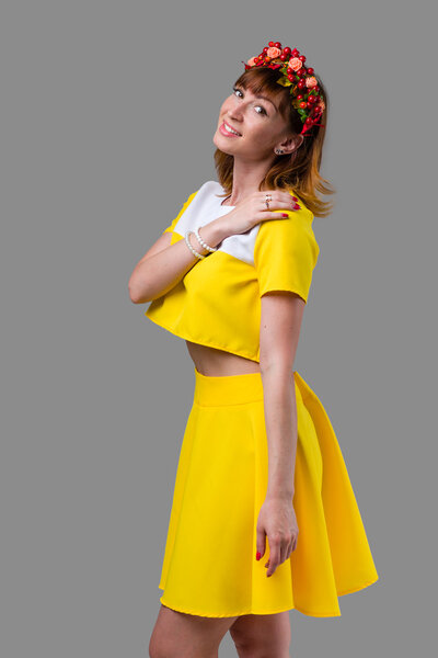 Woman in yellow dress with red wreath isolated on gray