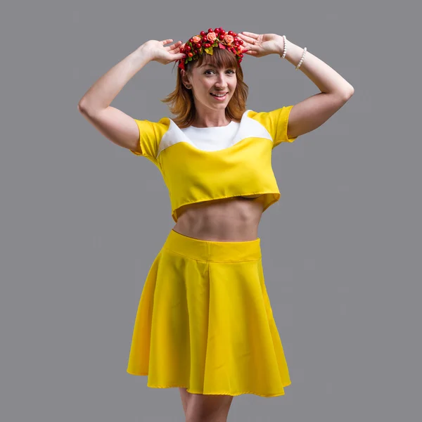 Femme en robe jaune avec couronne rouge isolée sur gris — Photo