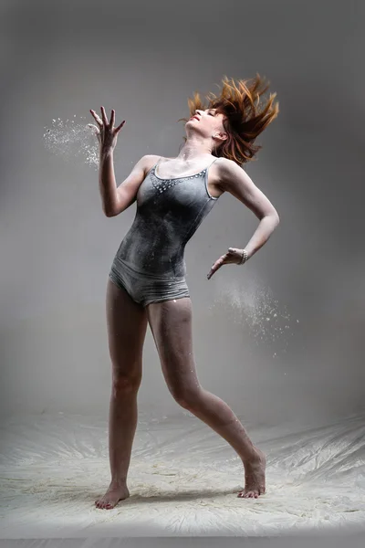 Beautiful expressive ballet dancer posing with flour at studio — Stock Photo, Image