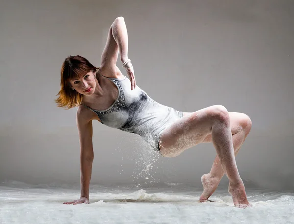 Beautiful expressive ballet dancer posing with flour at studio — Stock Photo, Image