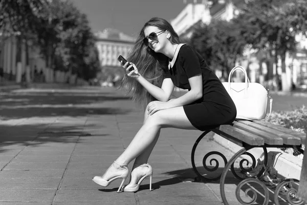 Молодая деловая женщина с телефоном сидит на скамейке — стоковое фото