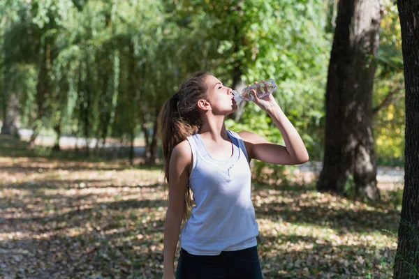 Jeune femme saine et sportive buvant de l'eau de la bouteille . — Photo