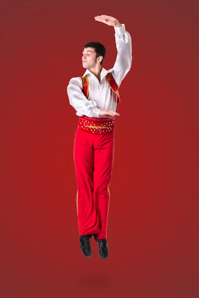 Jumping man wearing a toreador costume on red  in full length. — Zdjęcie stockowe