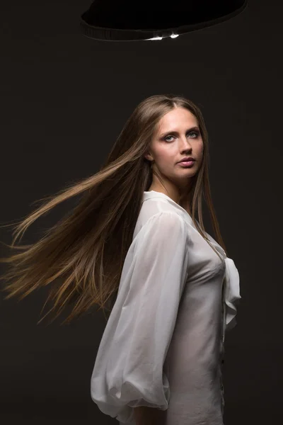 Retrato de una hermosa chica con el pelo volando sobre fondo oscuro en el estudio — Foto de Stock