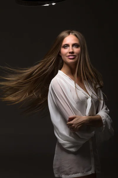 Portrait of a beautiful girl with flying hair on dark background in studio — Stock Photo, Image