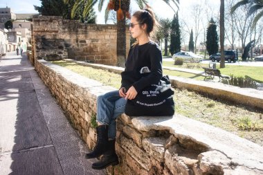 İspanya, Mallorca 'da Valldemosa' nın klasik kasabasında kot pantolon ve siyah beyaz ceketli genç bir manken..