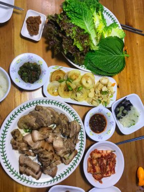 Domuz eti, soğan, kimçi, baharatlı biber, acı sos, sebze, soya ezmesi. Tipik çubuklu Kore yemek masası.