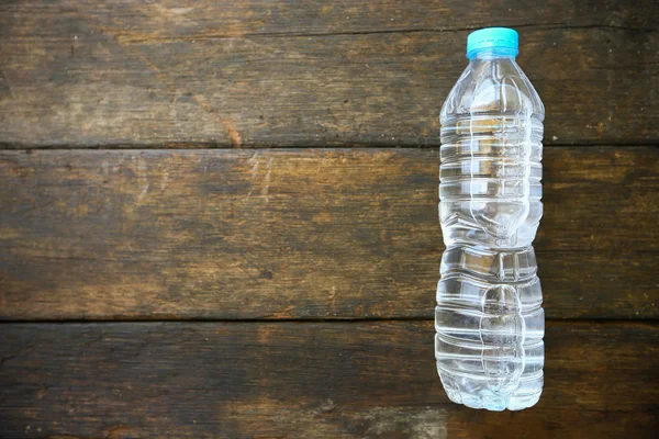 Agua dulce sobre fondo de madera, botella de agua de plástico con tapa azul en la mesa de madera, reciclaje de plástico de la botella de agua . — Foto de Stock