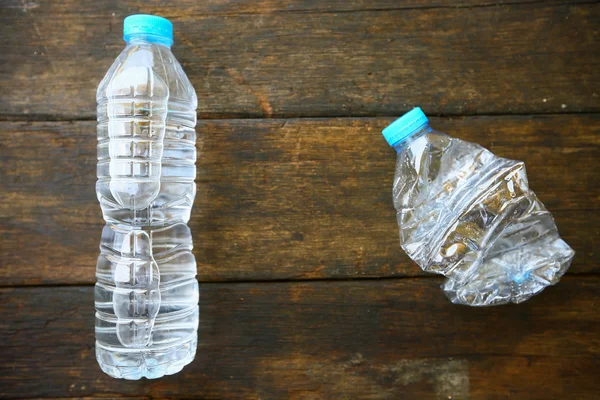 Agua dulce sobre fondo de madera, botella de agua de plástico con tapa azul en la mesa de madera, reciclaje de plástico de la botella de agua . — Foto de Stock