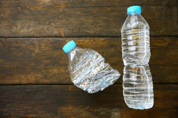 Agua dulce sobre fondo de madera, botella de agua de plástico con tapa azul en la mesa de madera, reciclaje de plástico de la botella de agua . — Foto de Stock