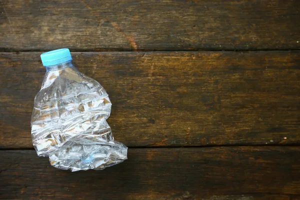 Agua dulce sobre fondo de madera, botella de agua de plástico con tapa azul en la mesa de madera, reciclaje de plástico de la botella de agua . — Foto de Stock