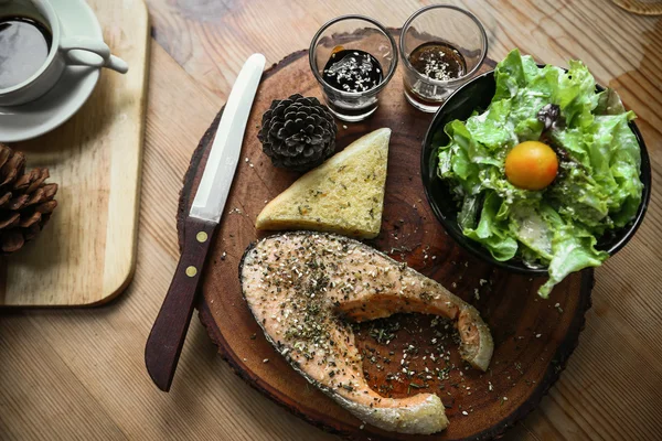 Salmon steak on wooden table in restaurant, Fresh steak for healthy food and clean food or fresh food for diet, International steak on plate with fresh vegetable or salad in the restaurant.