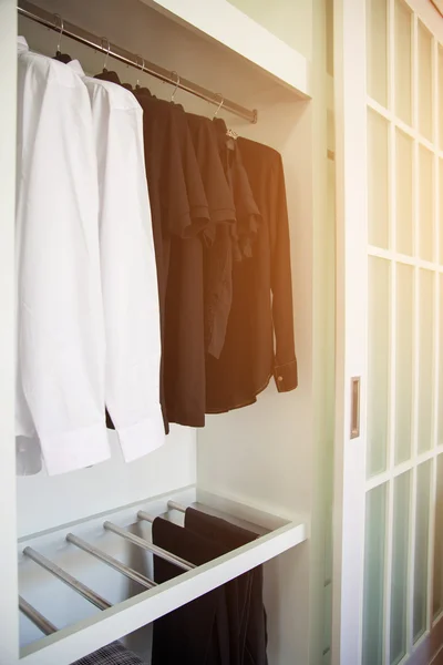 La ropa cuelga en un estante en una tienda de ropa de diseño, armario moderno con fila de ropa colgando en el armario, habitaciones vintage y pertenencias personales guardadas en la habitación que se sienten de lujo y relajarse . — Foto de Stock