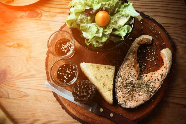 Salmon steak on wooden table in restaurant, Fresh steak for healthy food and clean food or fresh food for diet, International steak on plate with fresh vegetable or salad in the restaurant.