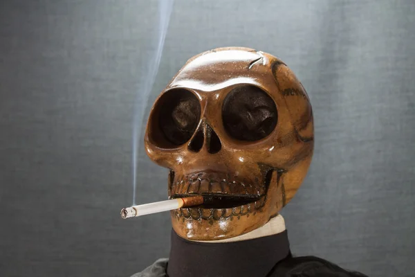 Menselijke schedel roken van een sigaret op een zwarte achtergrond, sigaret zeer gevaarlijk voor mensen. Gelieve niet roken. Halloween dag. — Stockfoto