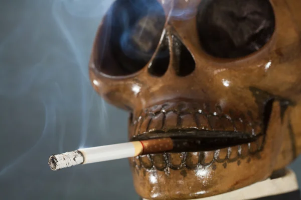 Menschlicher Schädel, der eine Zigarette auf schwarzem Hintergrund raucht, Zigarette sehr gefährlich für Menschen. Bitte nicht rauchen.halloween day. — Stockfoto