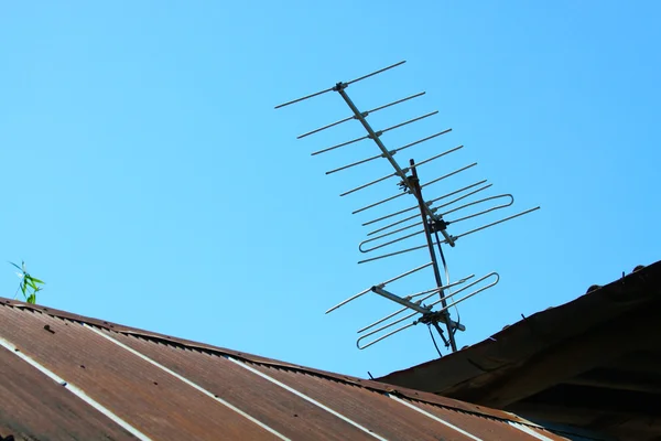 老房子屋顶与蓝天上的电视天线 — 图库照片
