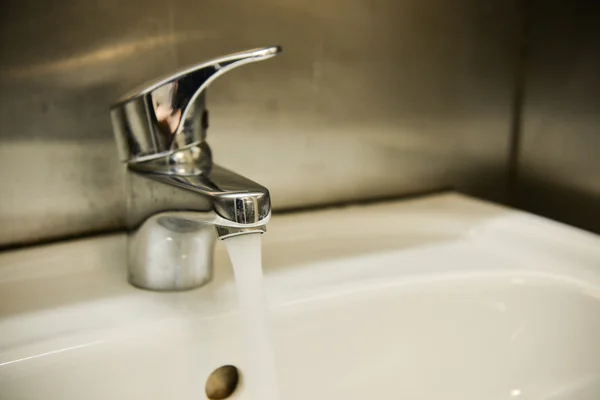 Fluxo de água da torneira no banheiro. Equipamento de casa de banho . — Fotografia de Stock
