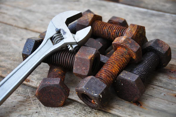 Oude bouten met verstelbare sleutel tools op houten achtergrond. — Stockfoto