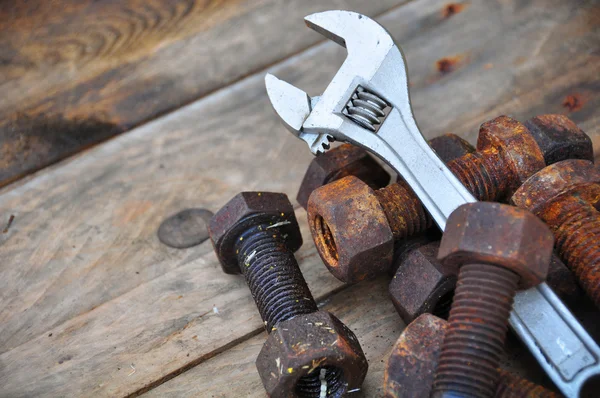 Oude bouten met verstelbare sleutel tools op houten achtergrond. — Stockfoto