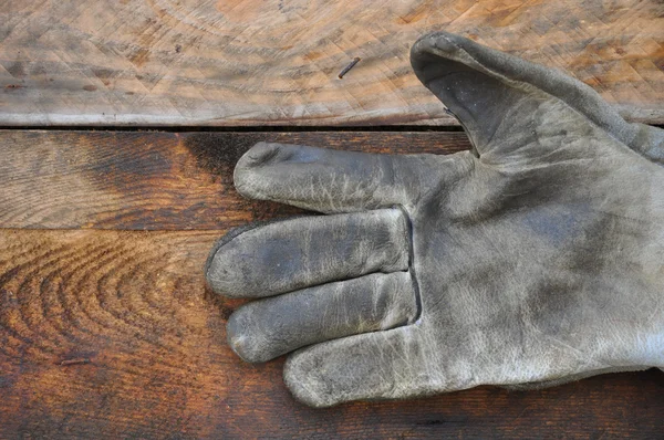 Старые перчатки безопасности на деревянном фоне, перчатки на грязных работах . — стоковое фото