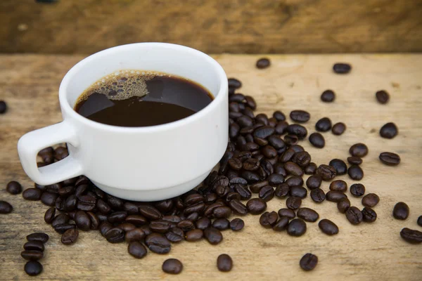 Fondo de granos de café en madera, Granos de café frescos con taza de café sobre fondo de madera, Fondo de juego de beber . — Foto de Stock